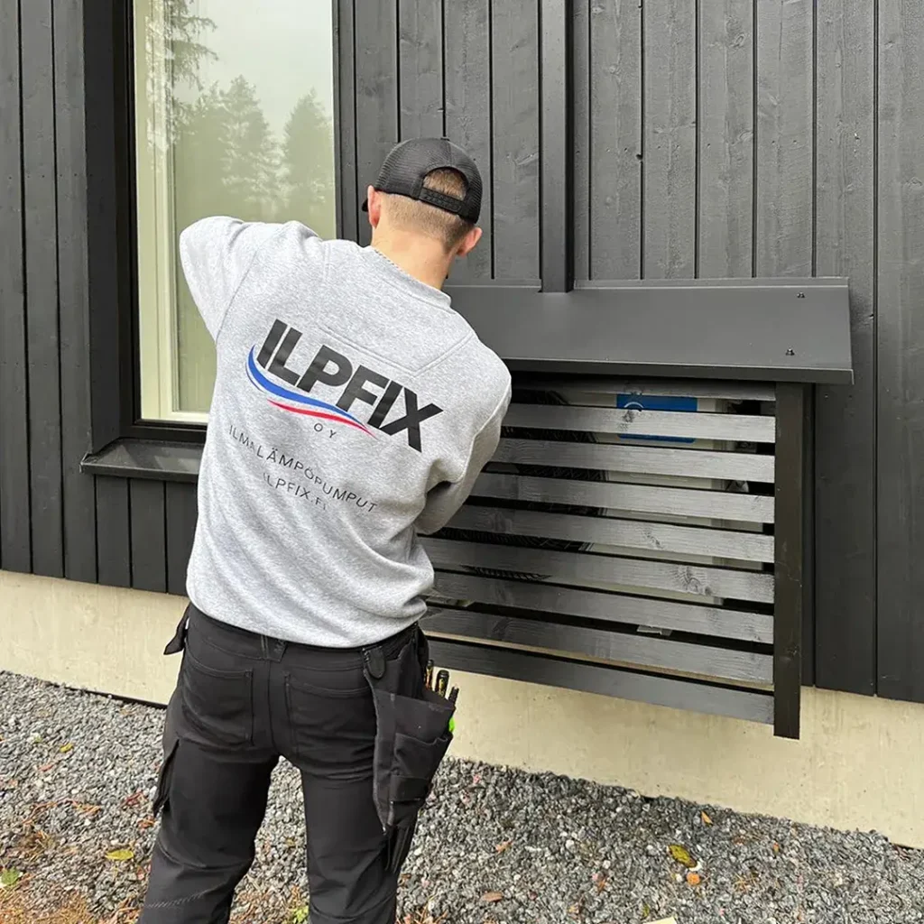 ILPFIX asentamassa mustaa ILPFIX-suojakoteloa mustan talon seinälle